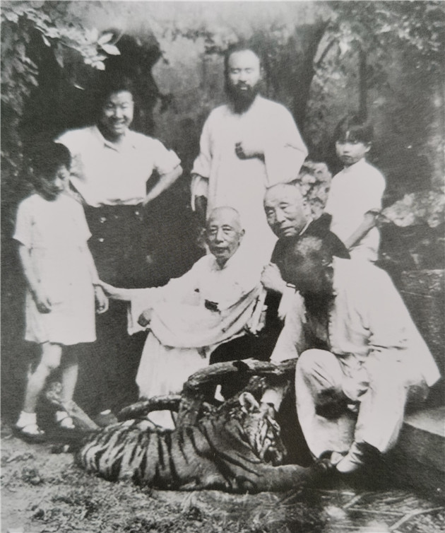 2李长慧（左）与父亲李宝常（中白衣坐者）、张大千（后排右二）、张善孖（逗虎者）等在苏州网狮园